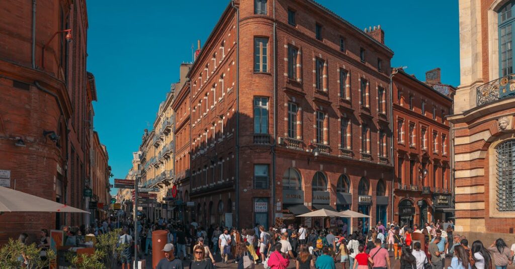 Scène de rue animée dans le quartier historique de Toulouse avec des foules et une architecture en briques rouges.